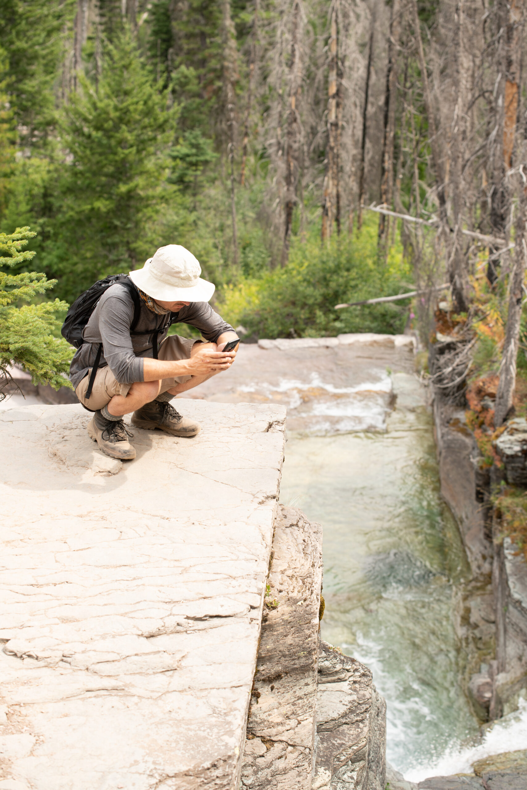 a man sitting on a rock looking at a phone