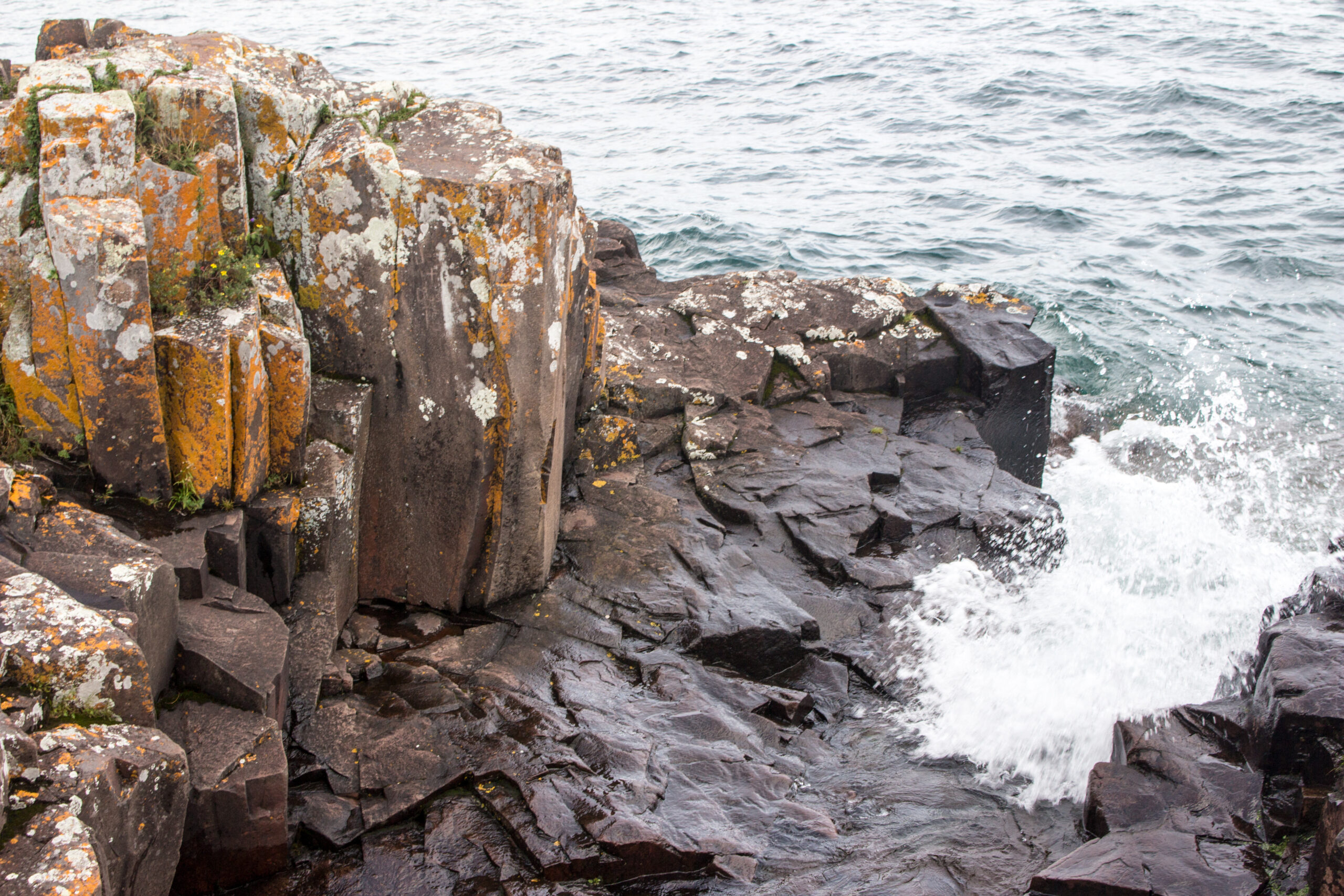 a rocky cliff with waves crashing on it