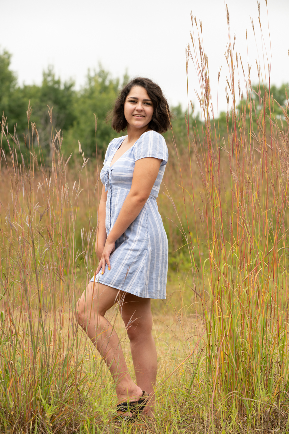a woman in a dress standing in tall grass