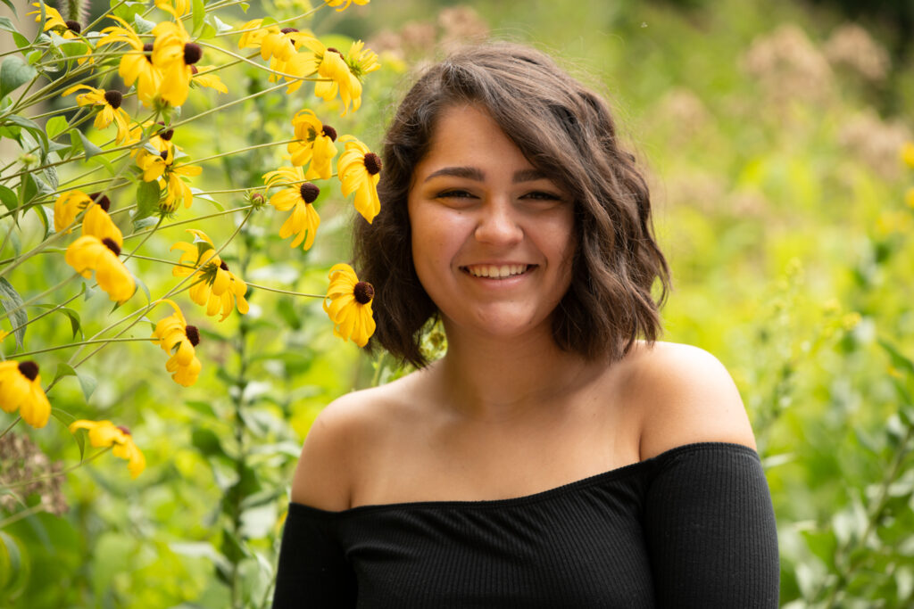 a woman smiling in front of yellow flowers