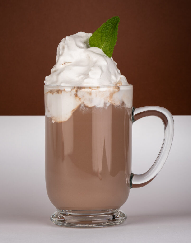 a glass cup with a drink and whipped cream on top
